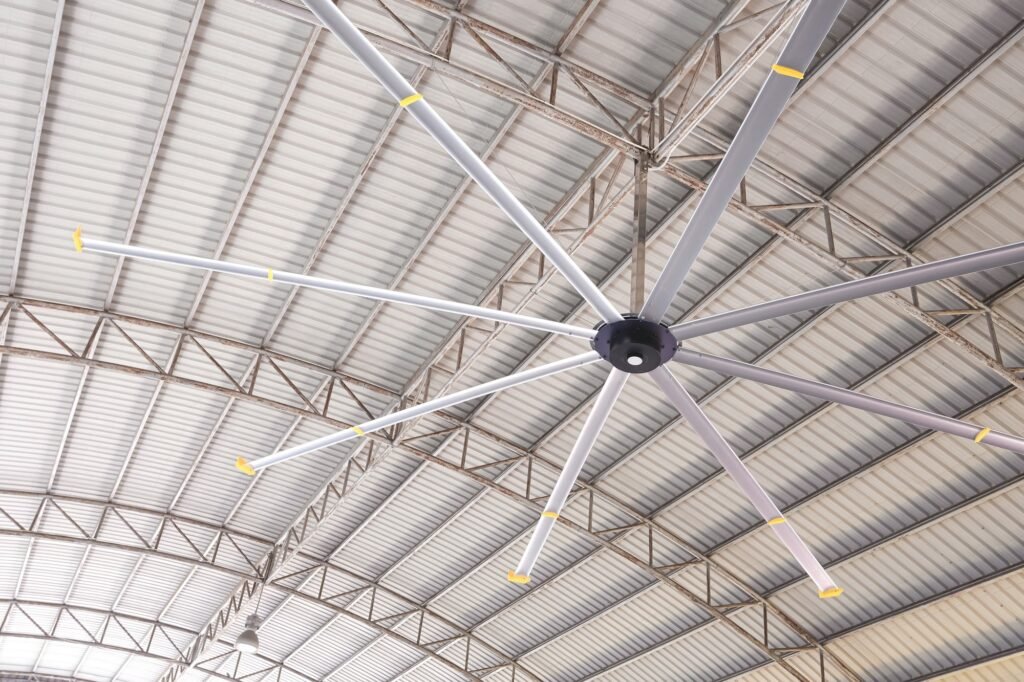 HVLS big fan on ceiling under the old metal curve roof structure of industrial building