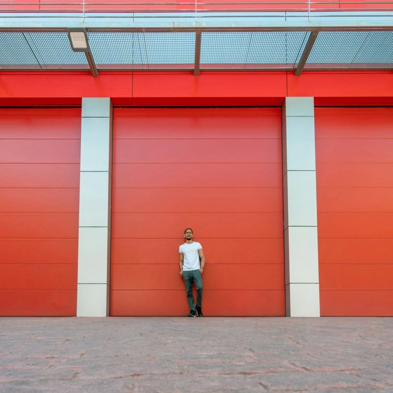 Man portrait leaning on a red warehouse door